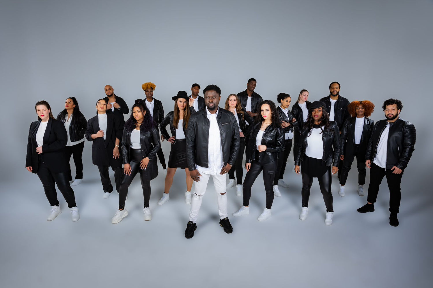 Ilaisa standing with Za-el gospel choir in studio, all wearing black leather jackets and white outfits