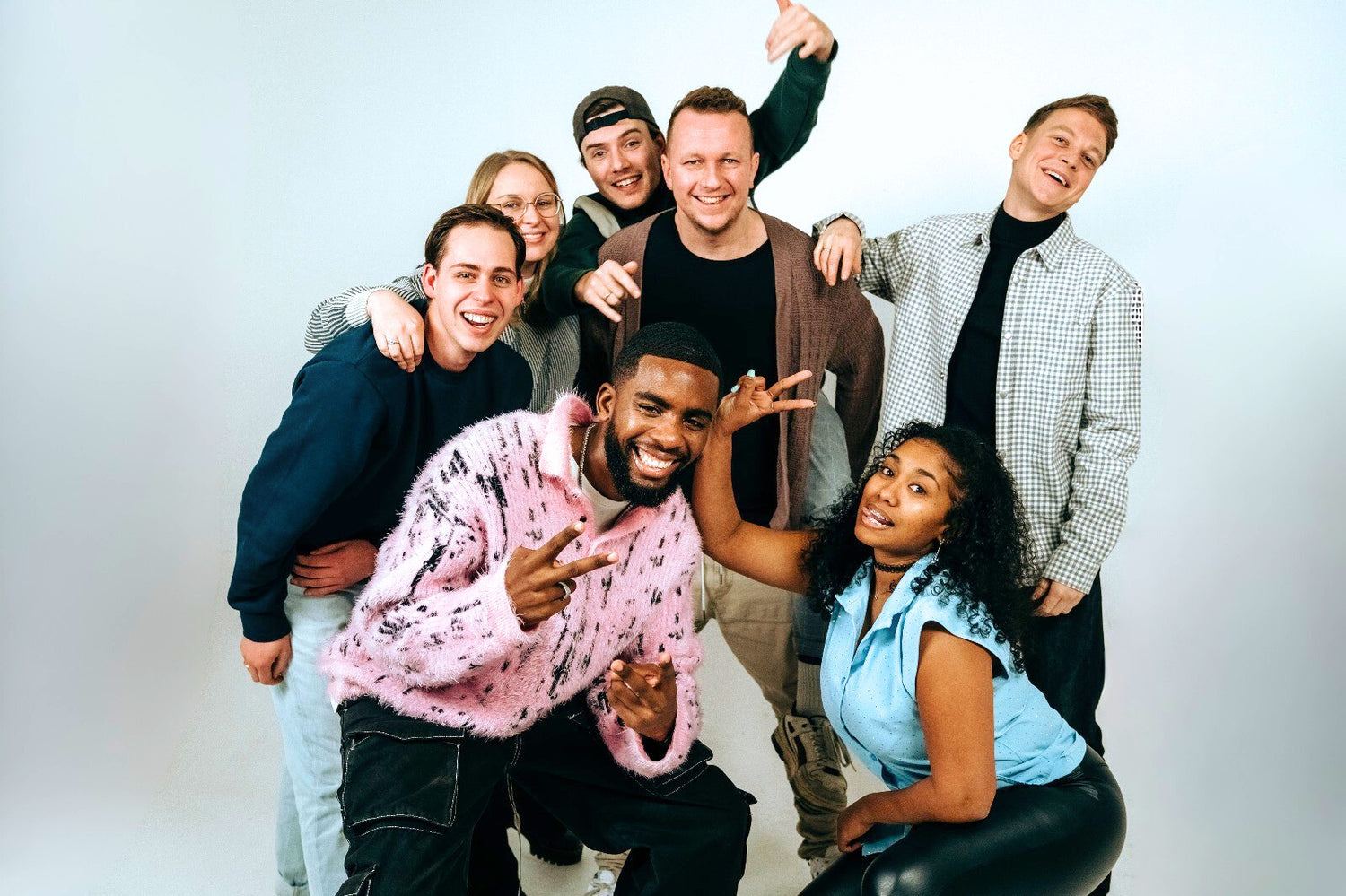 Current Beam band lineup posing together in studio, Ilaisa and six bandmates smiling and gesturing