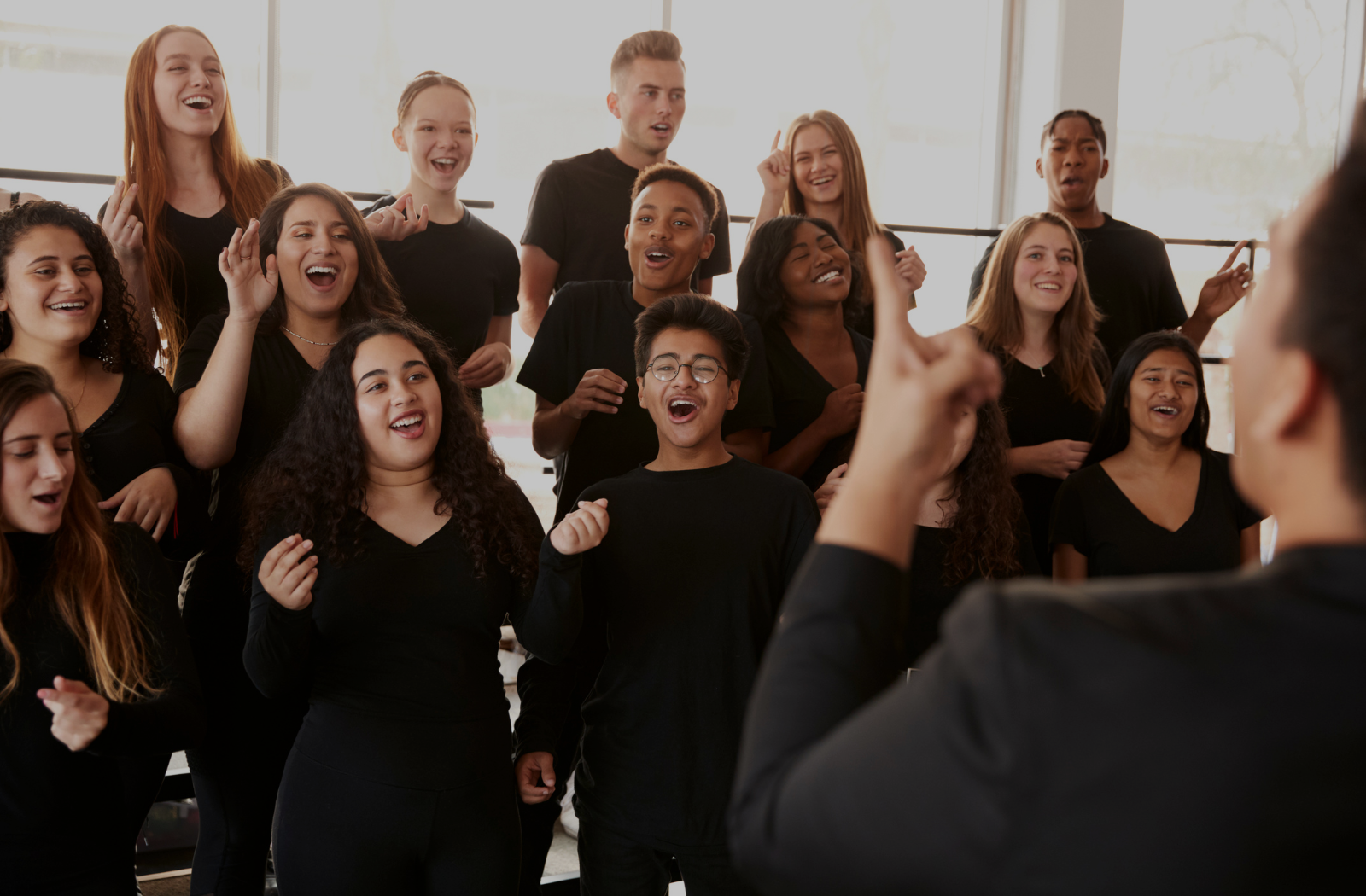 Choir of diverse singers rehearsing with conductor during group vocal workshop for Ilaisa’s private lessons page